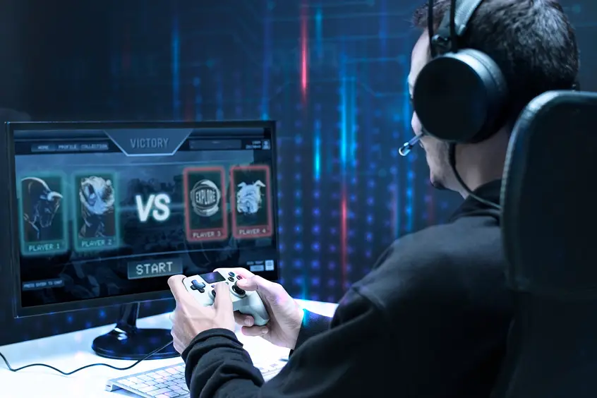 Een speler die met een controller speelt terwijl hij een koptelefoon draagt, en deelneemt aan een esports-wedstrijd die wordt weergegeven op een monitor met een versus-scherm en een spelinterface